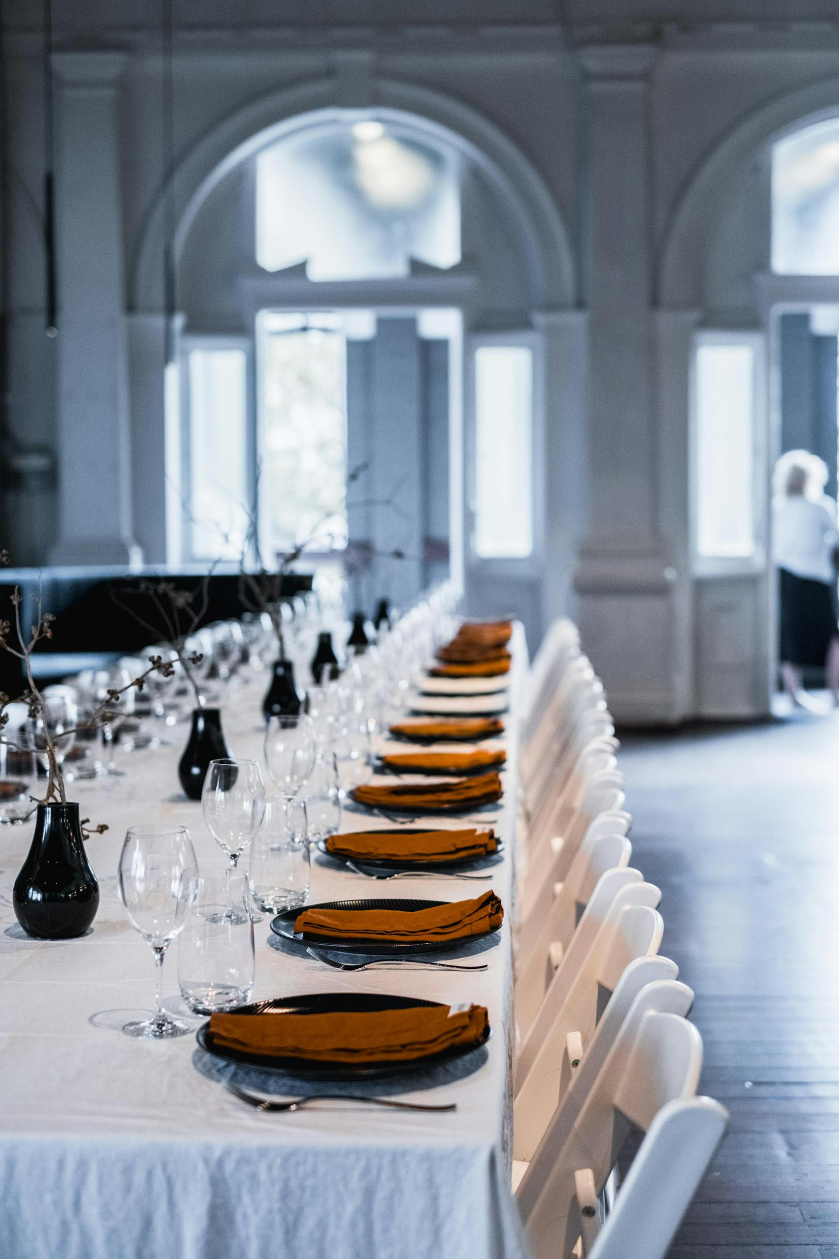 A beautifully set table with glassware and napkins in a sunlit event space, ideal for special occasions.