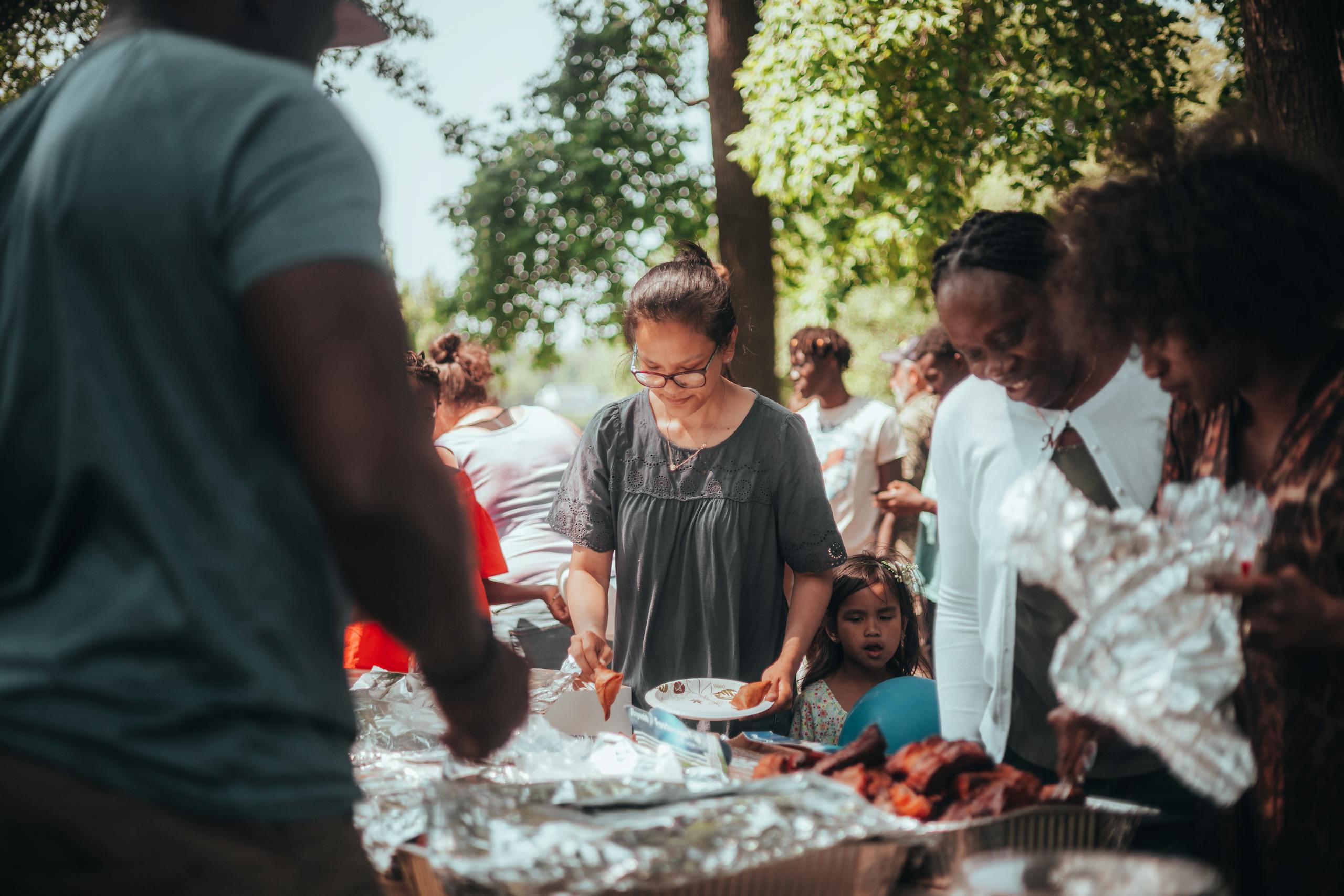A lively barbecue gathering with diverse group outdoors enjoying food and summer weather.